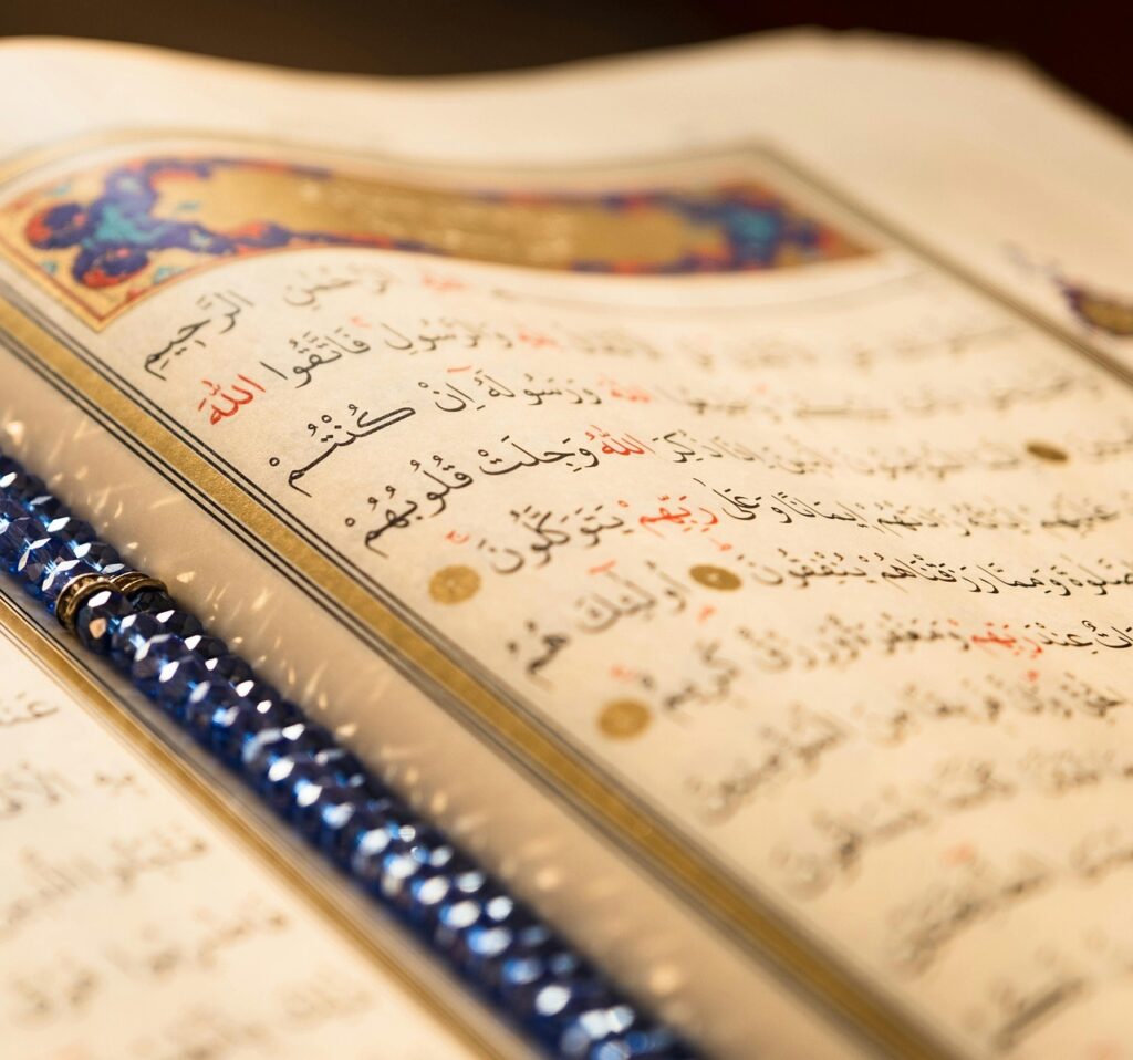 Gros plan d’une page du Coran ouverte avec calligraphie arabe, enluminures et marque-page, illustrant la lecture et la méditation quotidienne